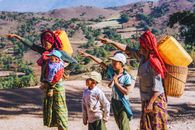 A rural family in Myanmar pointing in the countryside with baskets.