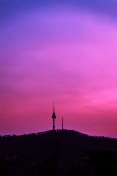 Silhouette of N Seoul Tower at sunset with dramatic purple sky.