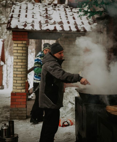 Free Man cooking outdoors in snowy Ust'-Kamenogorsk, Kazakhstan during winter. Stock Photo