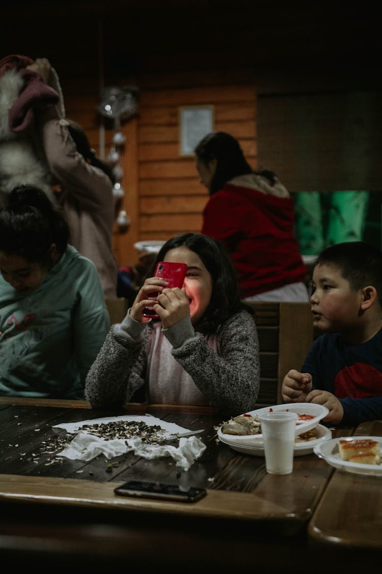 Children In Restaurant Playing With Phone