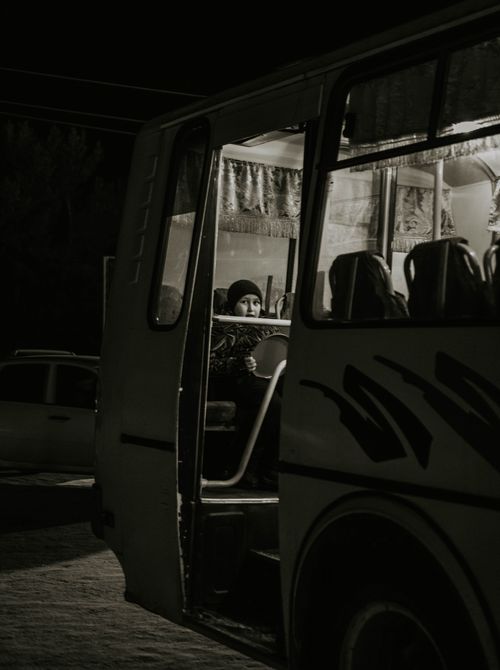 Free A child sitting on a bus at night, capturing the quiet moment of travel anticipation. Stock Photo