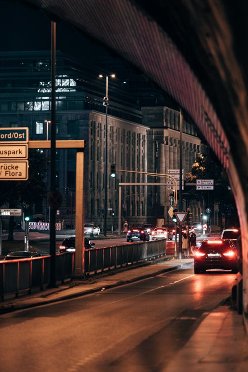 Free Illuminated city street at night with cars and buildings in an urban setting, showcasing nightlife and city living. Stock Photo