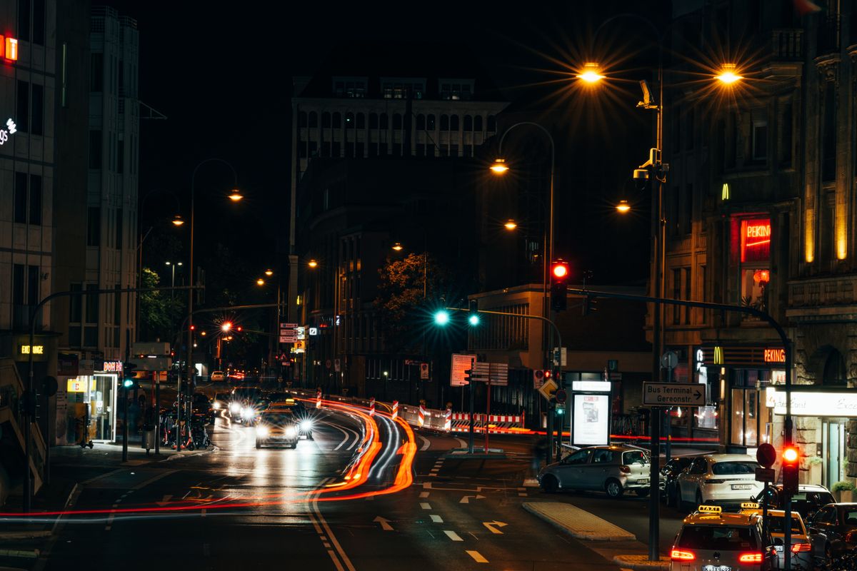 A bustling city intersection with night lights and streaking car trails.