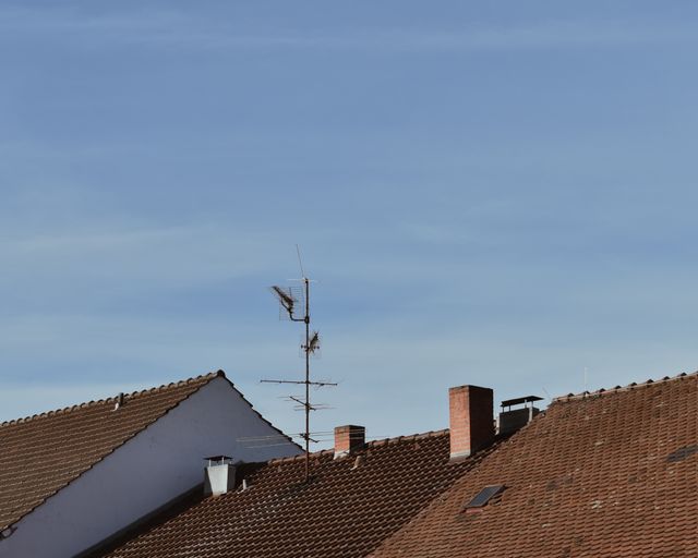 Neighborhood shingle rooftops Suburban rooftops with chimneys and windows under a clear blue sky