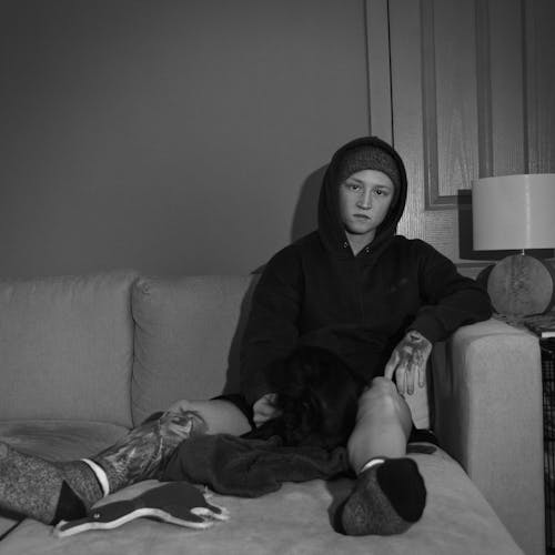 Person Wearing a Hoodie Sweater Sitting on a Sofa