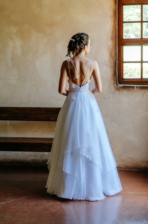 Woman in White Long Gown Standing Near the Window