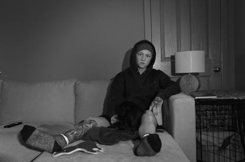 Grayscale Photo of Person Sitting on a Couch