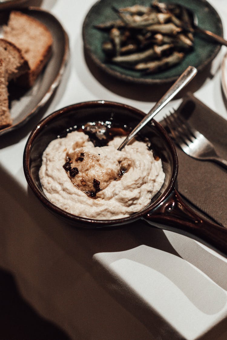 Bowl Of Appetizing Humus Placed On Table During Dinner In Restaurant