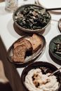 High angle plate of fresh bread served on table near bowls of humus and green salad during dinner in restaurant