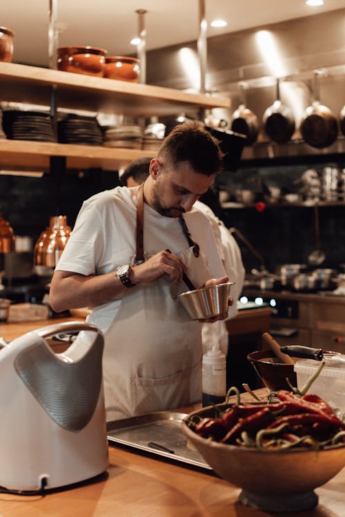 Serious man cooking food at table in restaurant kitchen