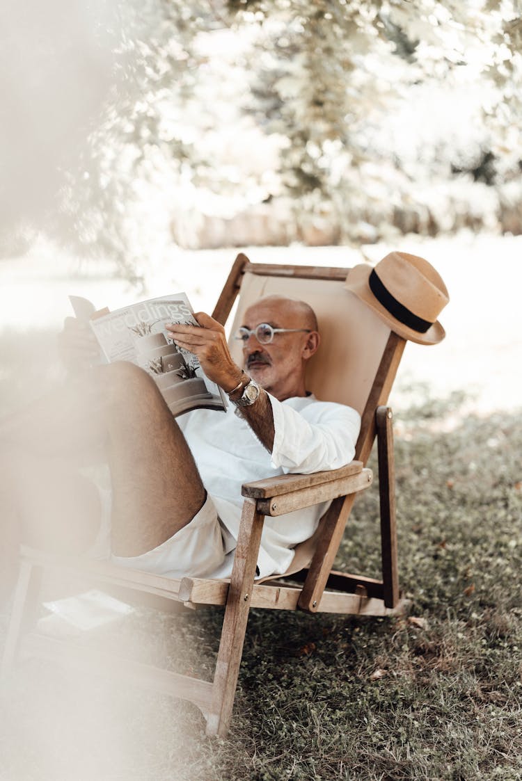 Pensive Ethnic Man Reading Magazine In Nature