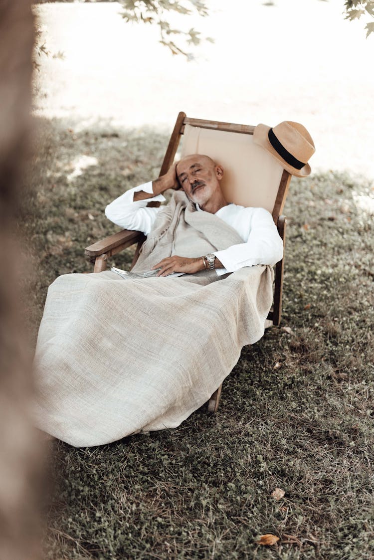 Senior Ethnic Man Sleeping On Chair In Nature