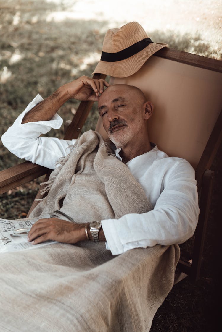 Senior Ethnic Man Sleeping On Chair In Nature