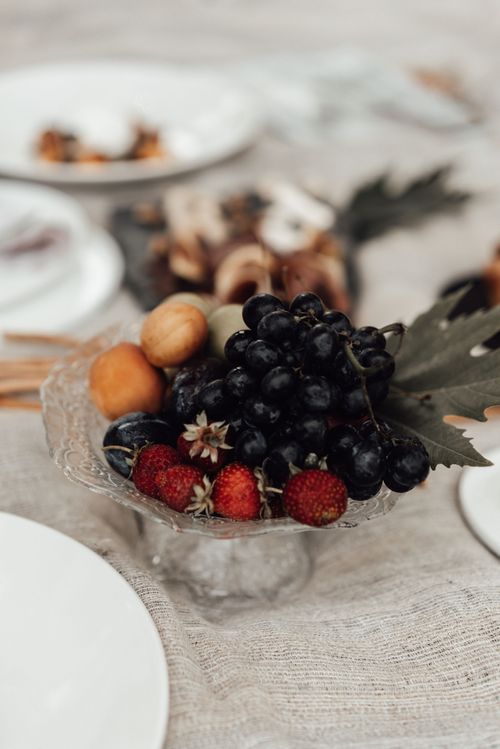 Free High angle of bowl with fresh strawberries and grapes near nectarines on textile near plates with food Stock Photo