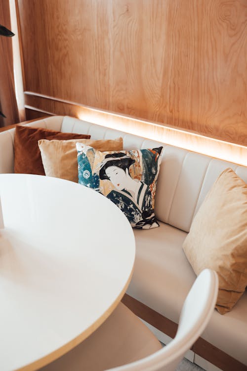 High angle of comfortable sofa with soft cushions placed near white round table in modern cafe