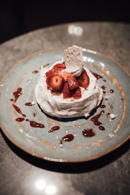 Free From above of plate with delicious famous Pavlova cake garnished with strawberries and sauce and served on table in cafe Stock Photo