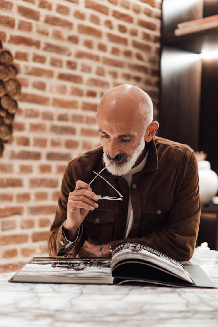 Focused Senior Ethnic Man Reading Book In Cafe