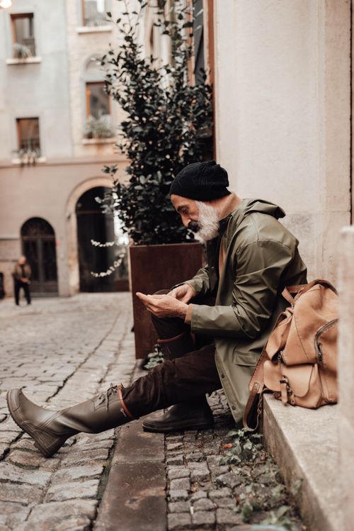 Free Side view of mature ethnic male tourist in outerwear browsing internet on mobile phone in town Stock Photo