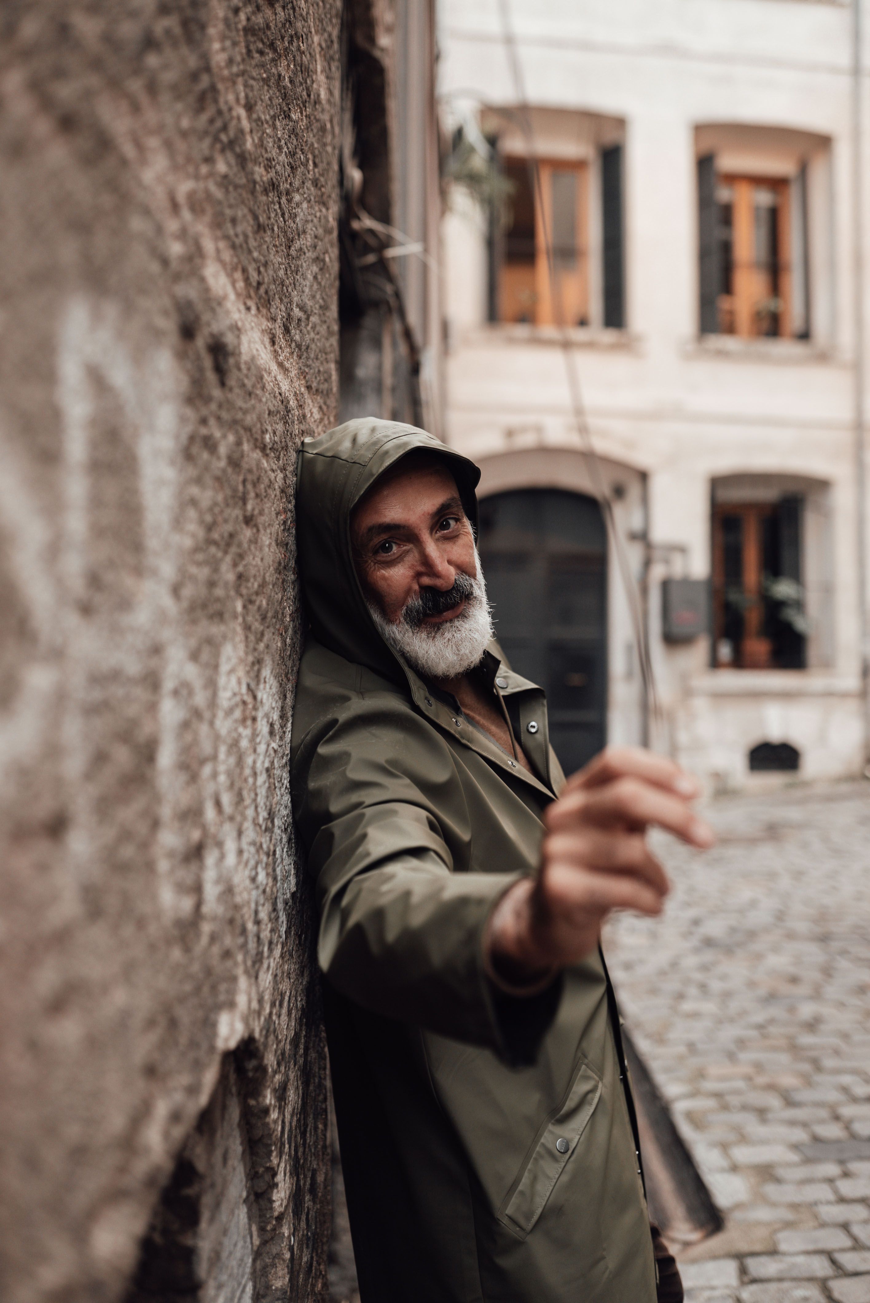 Side view of content middle aged ethnic male with gray beard looking at camera in old town