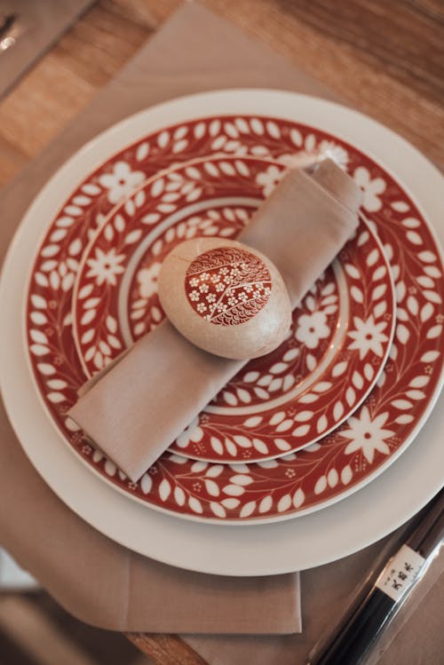 From above Easter egg placed on festive red plate on wooden table with napkins in daytime