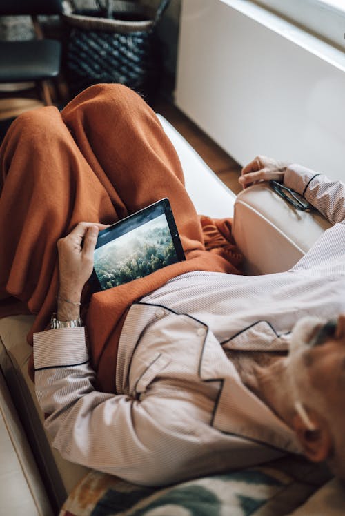 Free Ethnic man sleeping while watching video on tablet and sitting on couch Stock Photo