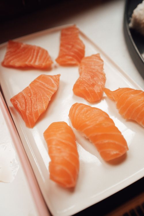 Free From above of slices with raw red salmon on plate on white surface in light room Stock Photo