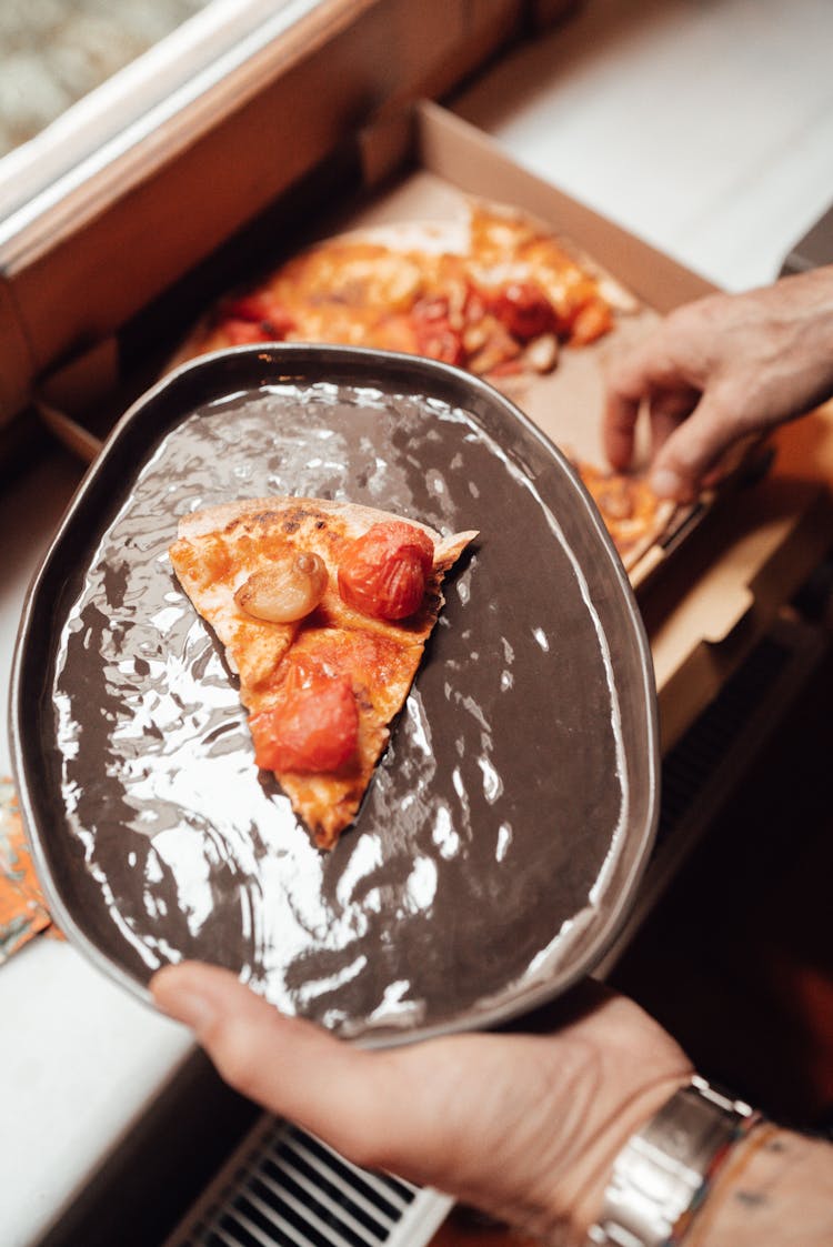 Anonymous Man With Pizza Slice On Plate Near Windowsill