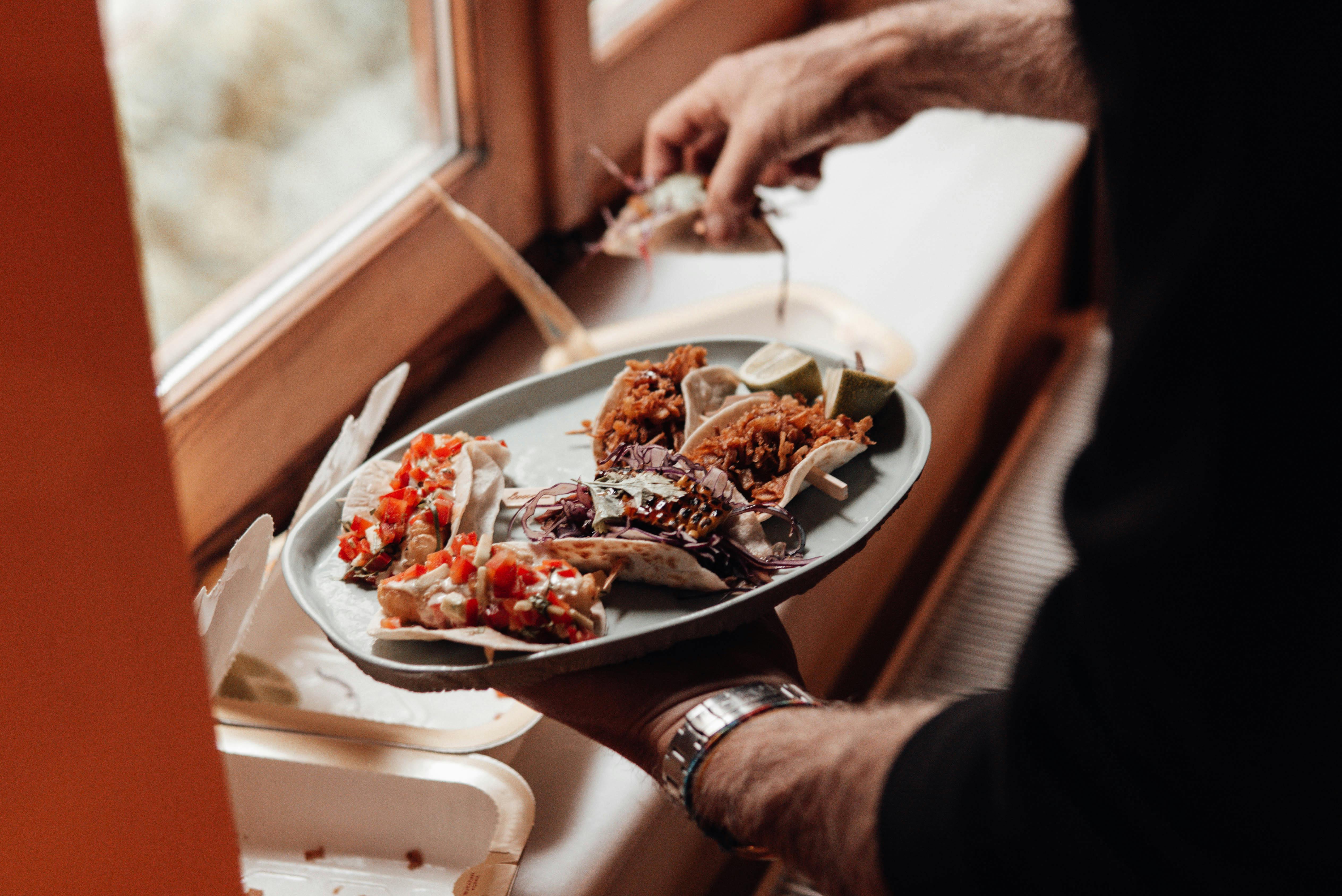 unrecognizable male with plate with various tacos near containers