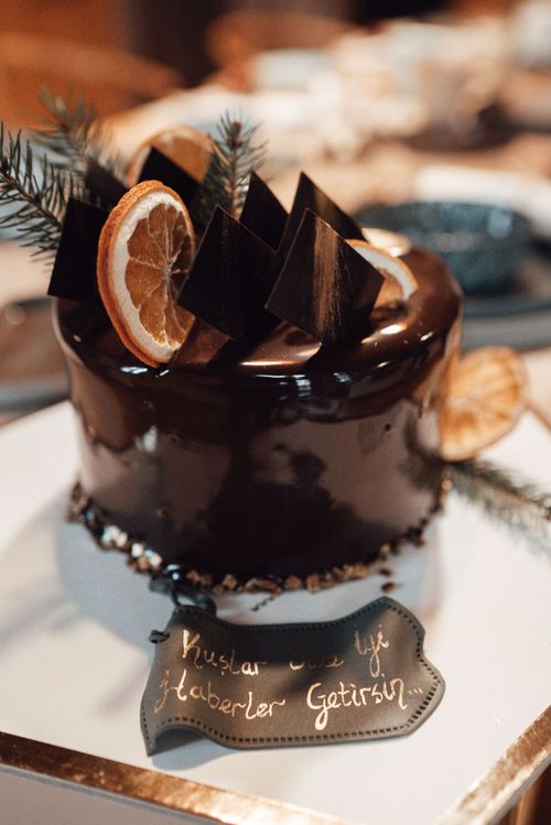 Free High angle of tasty chocolate cake decorated with slices of dried oranges and spruce sprigs near plaque with inscription placed on plate near table in light restaurant Stock Photo