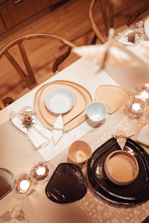 Free Top view of table setting with various tableware with bowls placed near burning candles and folded napkins in kitchen with hanging orizurus Stock Photo