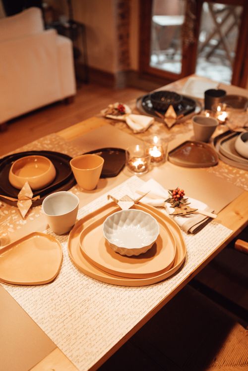 Free From above of various dishware with cups placed on table with candles and decorative paper cranes in modern dining room Stock Photo