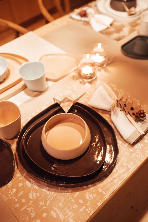 Free From above of tableware with various tableware with cups and folded napkin near burning candle in kitchen at home Stock Photo
