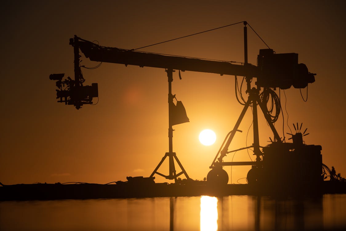 Modern equipment for filming process in pond against bright sun shining on sunset sky