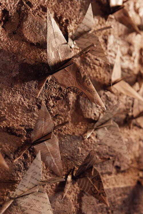 Abundance of traditional handmade orizurus made of paper hanging on decorated rough stone wall in room with creative decorations at home