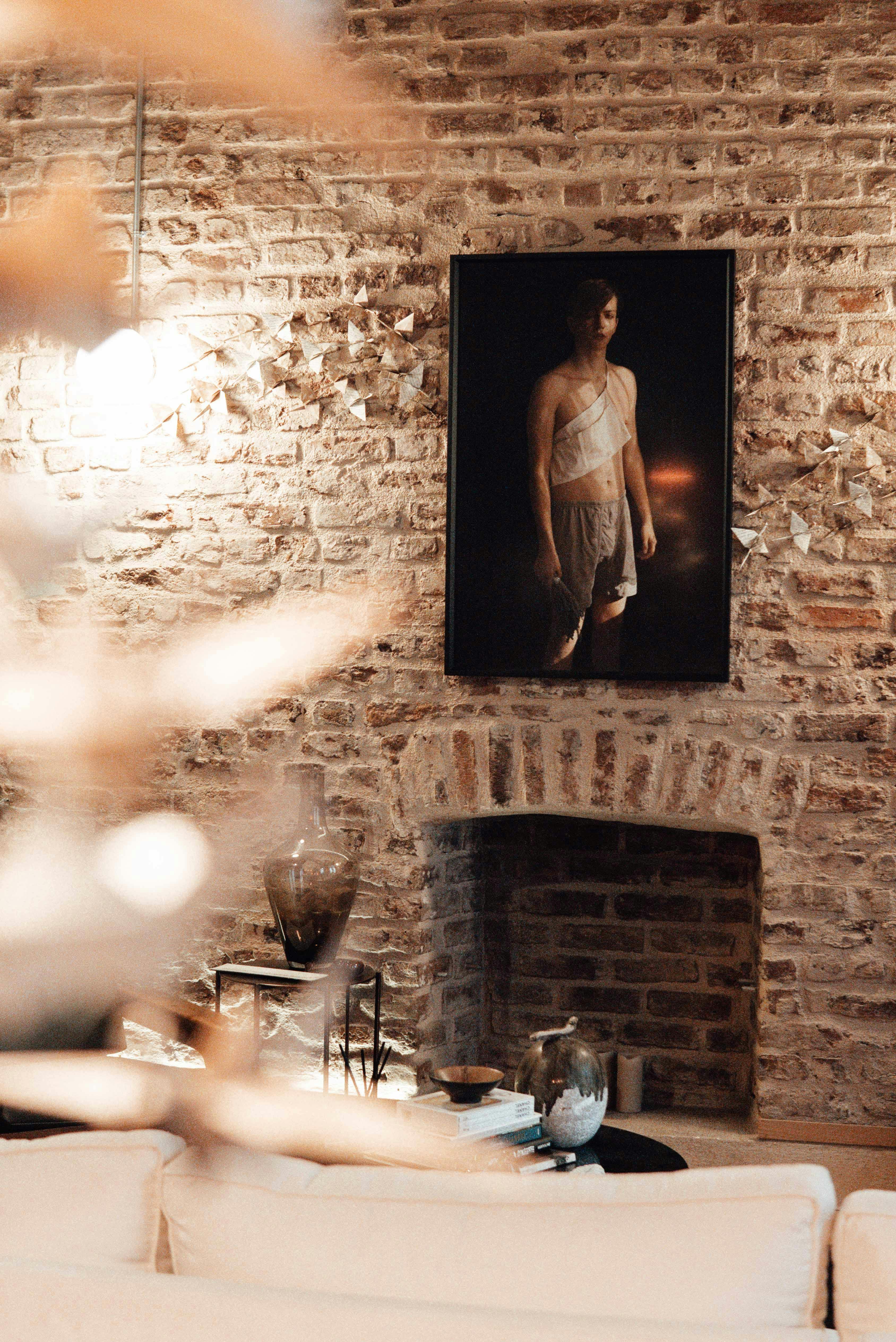 Table with served tableware placed near decorated brick wall with picture in light room with lamp and hanging paper cranes