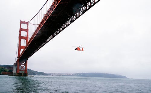 бесплатная Спасательный вертолет, летящий под мостом Золотые Ворота Стоковое фото