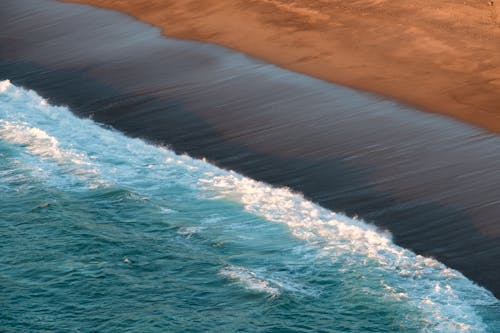 Foaming sea rolling on wet sandy beach