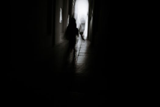 Blurred silhouette of a person walking down a dark and eerie corridor.