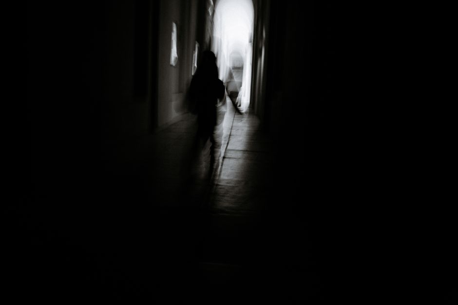Blurred silhouette of a person walking down a dark and eerie corridor.