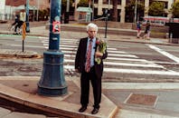 旧金山充满活力的城市景象中，人行横道上捧着鲜花的老人