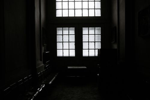 Free A dimly lit interior hallway featuring tall frosted glass doors creating a moody atmosphere. Stock Photo