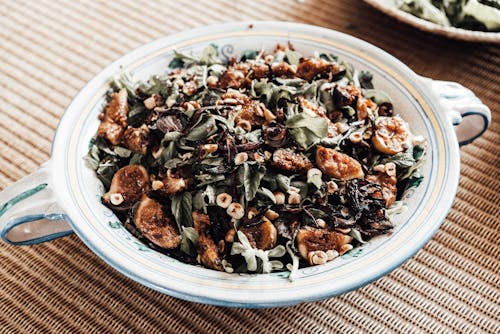 Delicious healthy fig and arugula salad with cut nuts served on plate on table