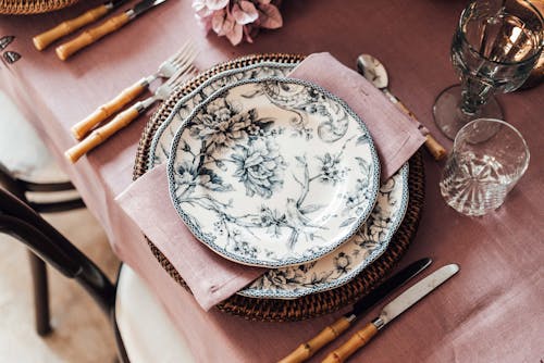 From above of plates and napkin placed near flatware on tablecloth covering table for festive event