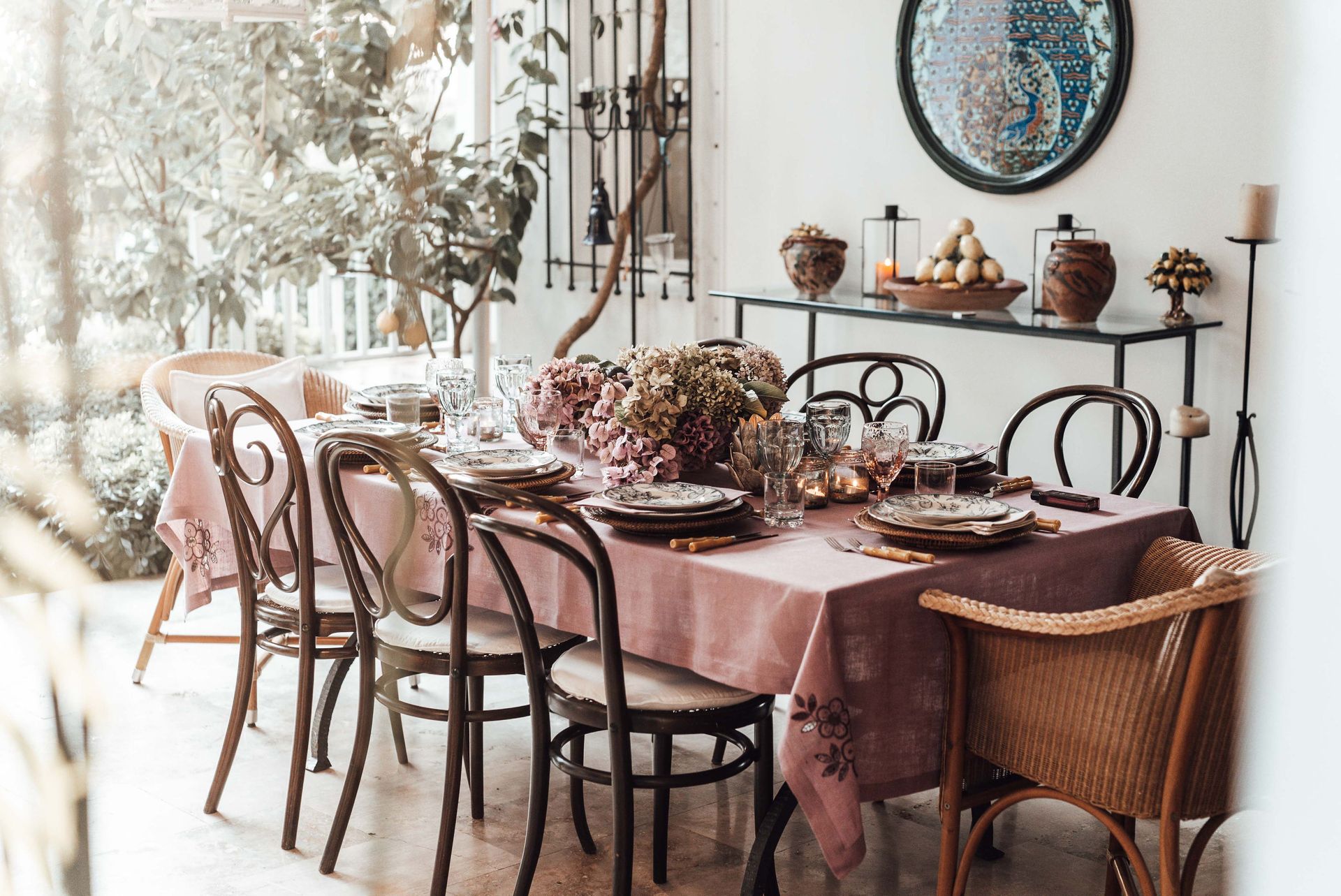 A beautifully decorated table setting for a dinner party, featuring floral arrangements and elegant dishware in an outdoor garden setting.