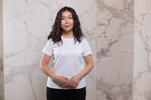 Content Asian woman standing against marble wall
