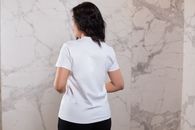 Back view positive female wearing black pant and white t shirt standing against marble wall