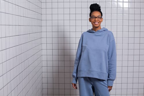 Happy black woman in blue comfy wear against tiled wall