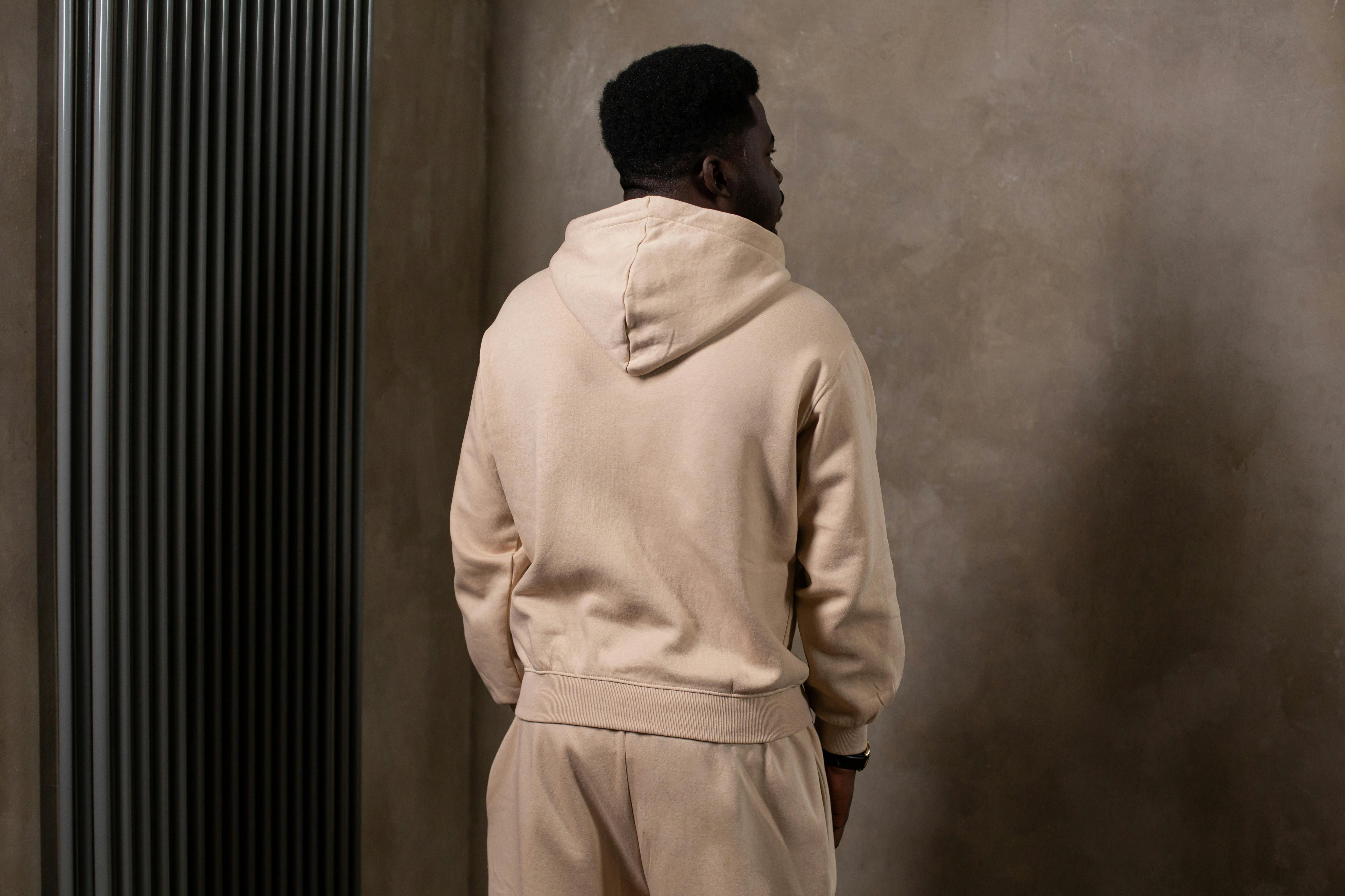 African American man in beige activewear standing indoors, looking away with a contemplative pose.