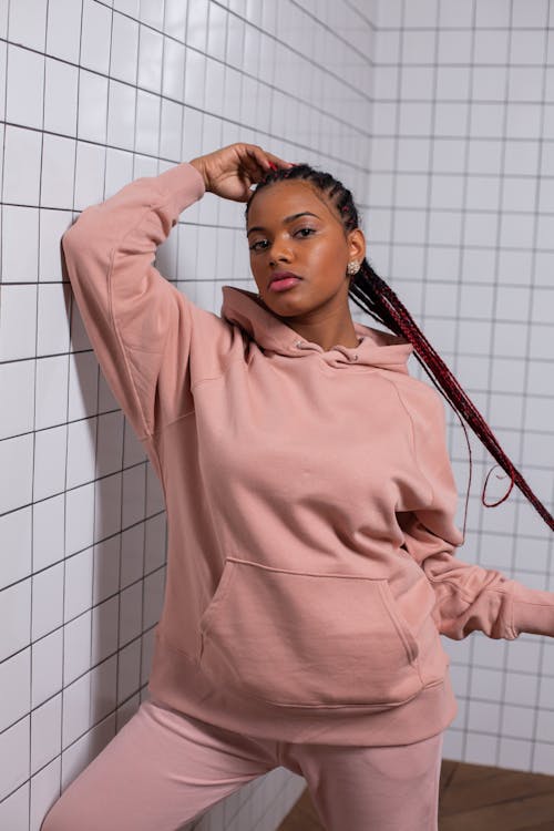 Confident young black lady touching braided hair and looking at camera