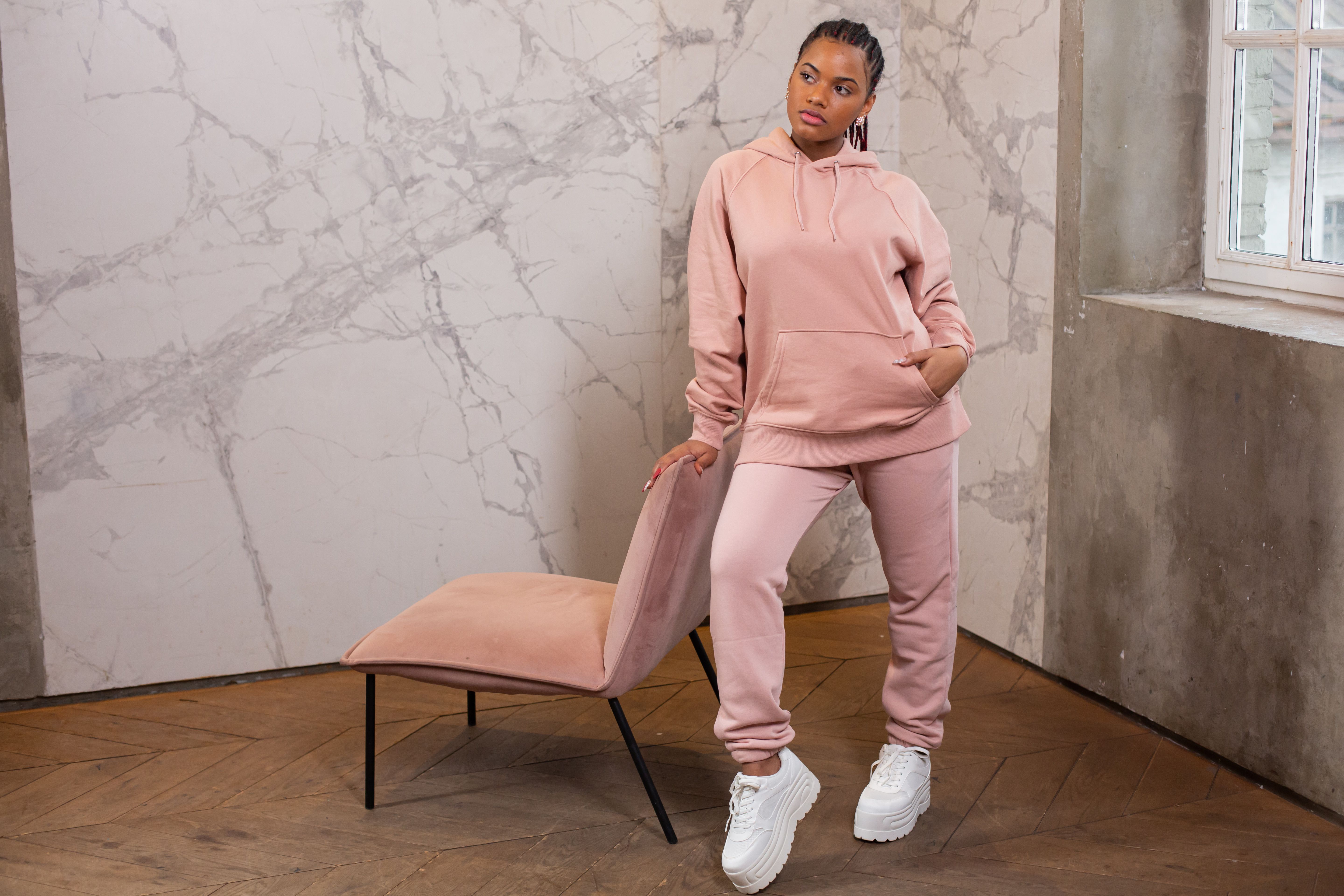 Femme en ensemble jogging rose oversize dans un intérieur moderne épuré